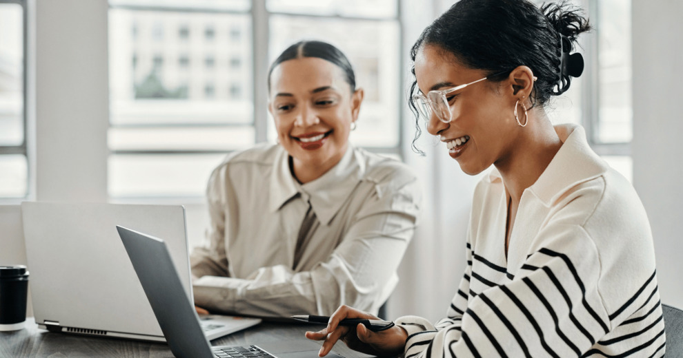 Two colleagues reviewing work together at a laptop in an office