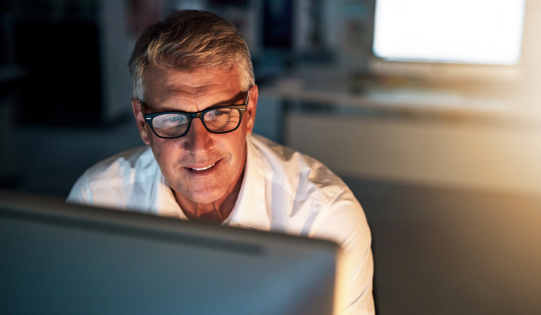 Man sitting at computer at night smiling because his emails are secure