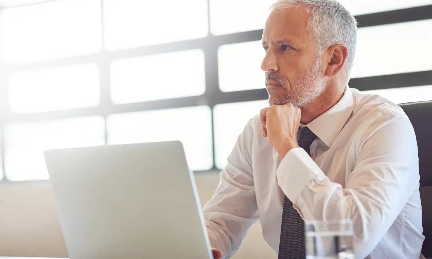 Male professional thinking by laptop about securing cutomer data