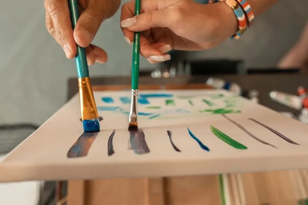 An artist testing brushstrokes of paint on a blank canvas