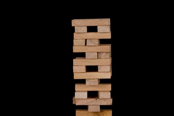 A tower of wooden blocks stacked precariously against a black background