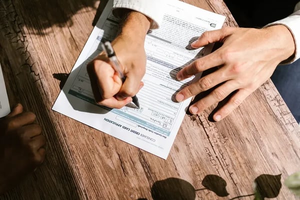 Two people filling in a printed consumer credit card application form