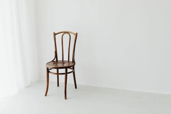 An empty wooden chair in a bare, brightly lit room