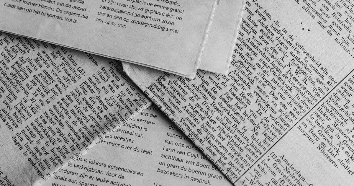Overlapping pages of printed newspaper in black and white