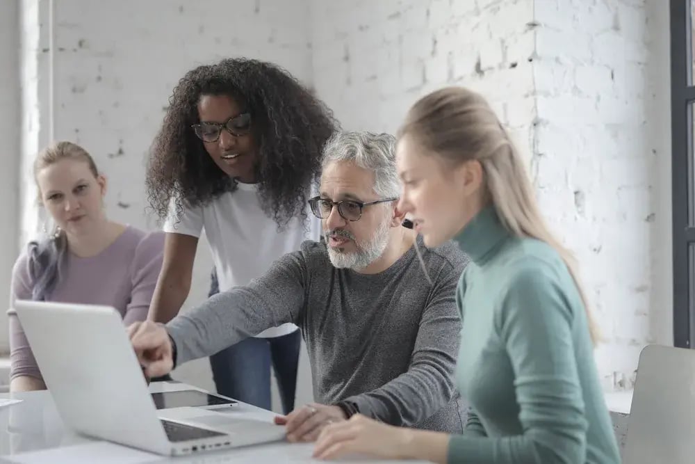 A team collaborating around a laptop