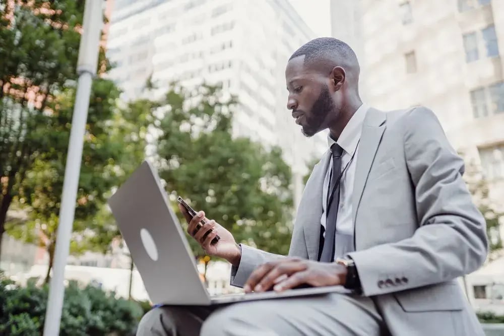 A professional using a smartphone and laptop