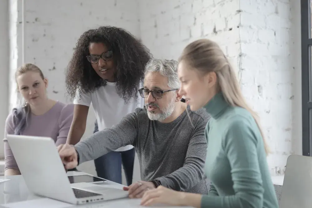 A team collaborating around a laptop