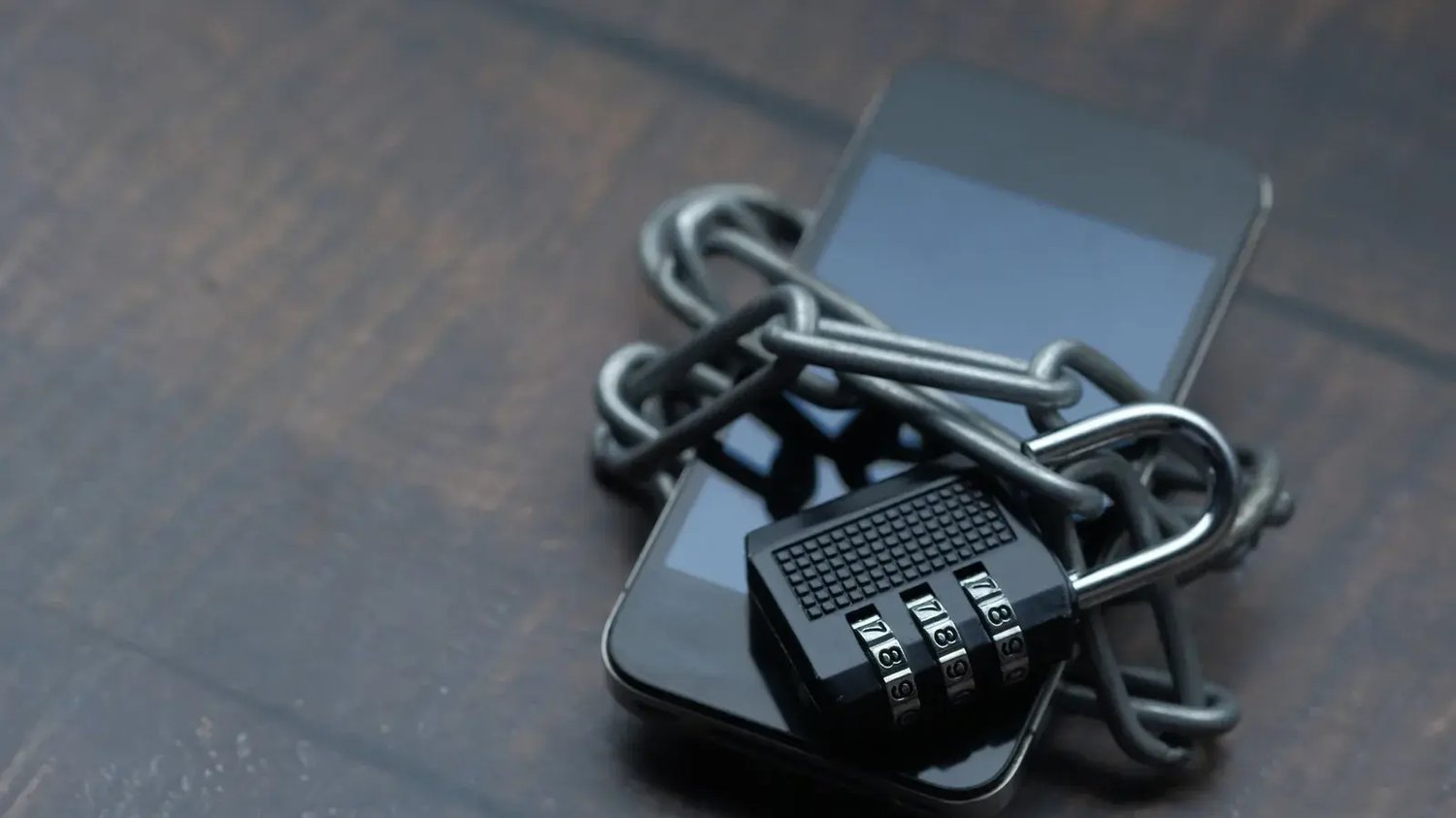 A smartphone secured with a chain and padlock