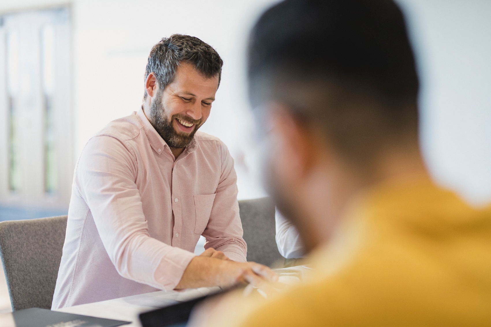 Male professional smiling with colleague in office about new secure email system