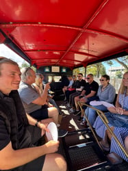 The Beyond Encryption team sitting together on a vintage open-top vehicle in the sunshine, celebrating CEO Paul Holland's birthday