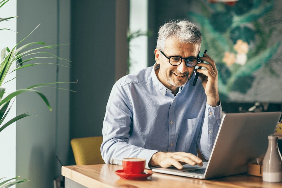 Professional using laptop while on phone, representing secure email communication and protected information sharing with Mailock