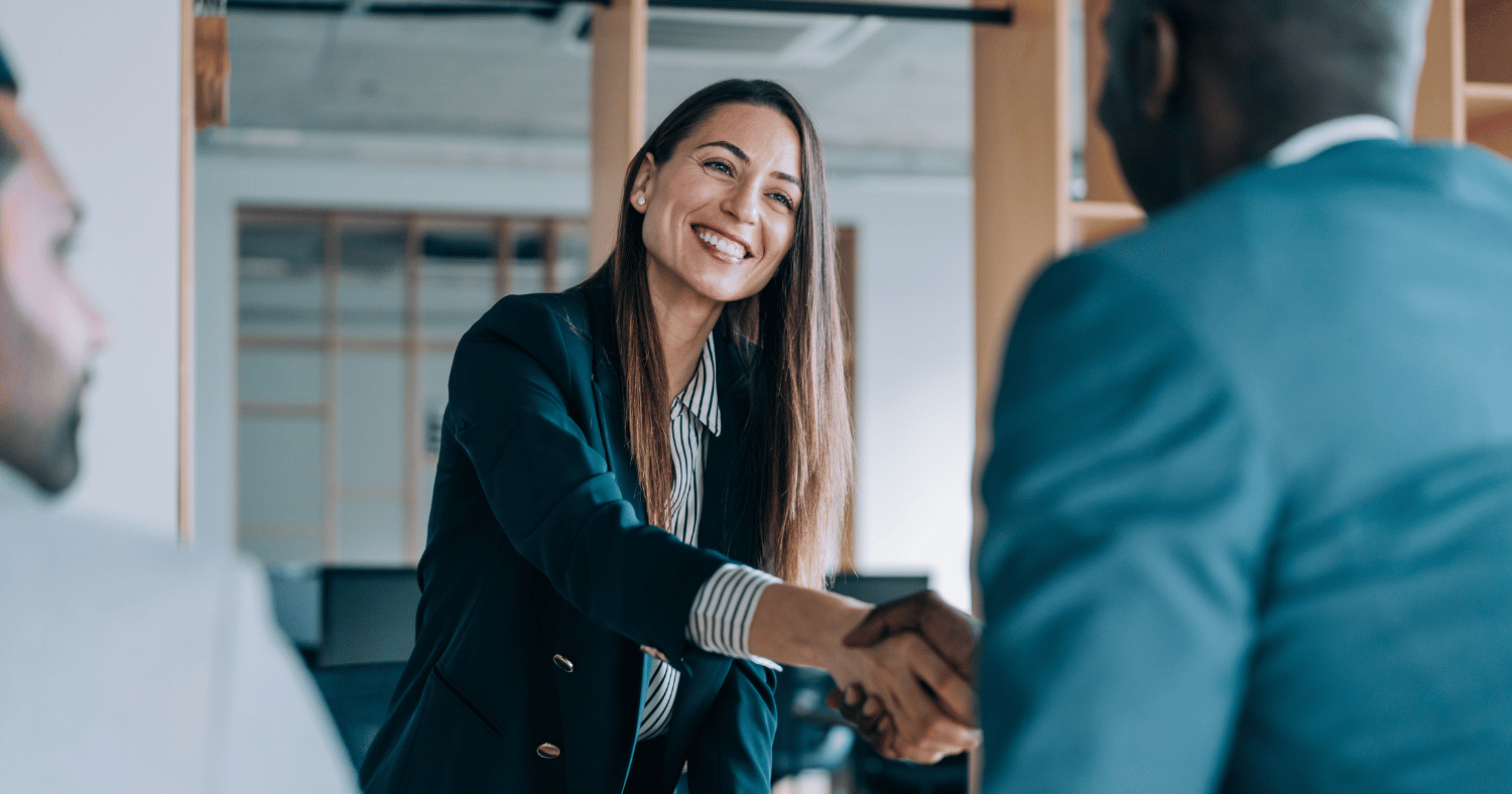 Woman shaking hands with two men in office